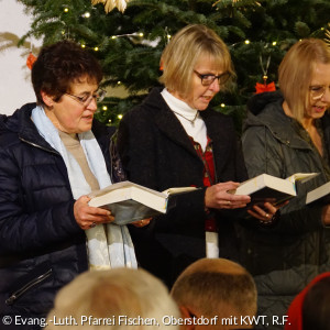 Drei Ehrenamtliche singen aus dem Gesangbuch
